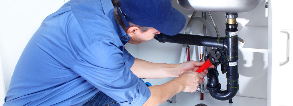 plumber repairing drain under sink