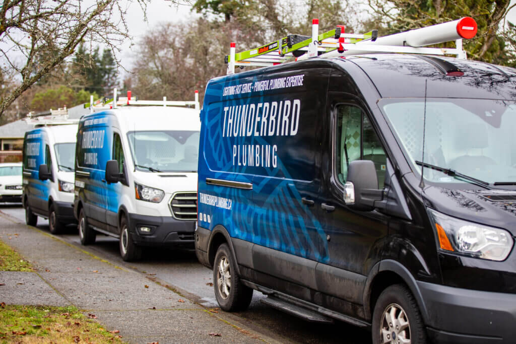 Thunderbird plumbing trucks lined up on residential street.
